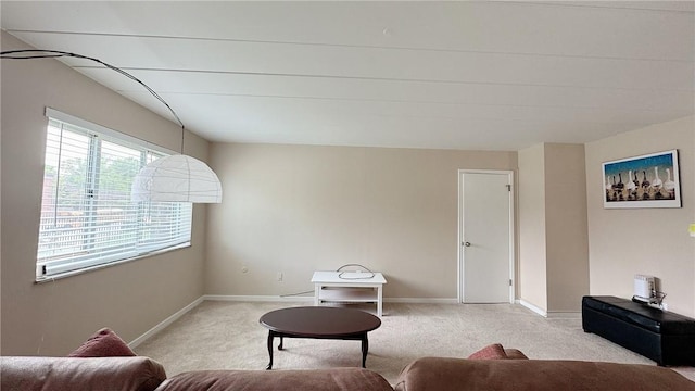 living area featuring light carpet and baseboards