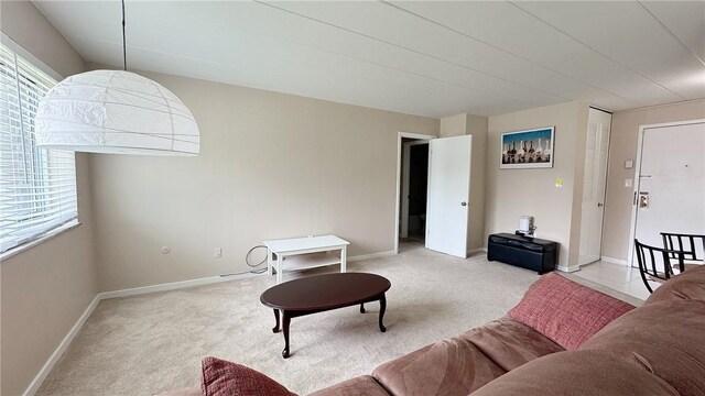living area featuring light carpet and baseboards