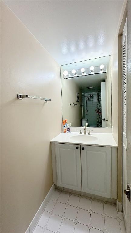 bathroom featuring walk in shower, vanity, baseboards, and tile patterned floors