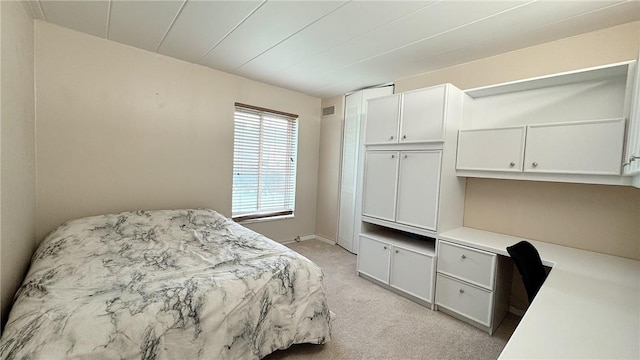 bedroom with built in desk, light carpet, and visible vents