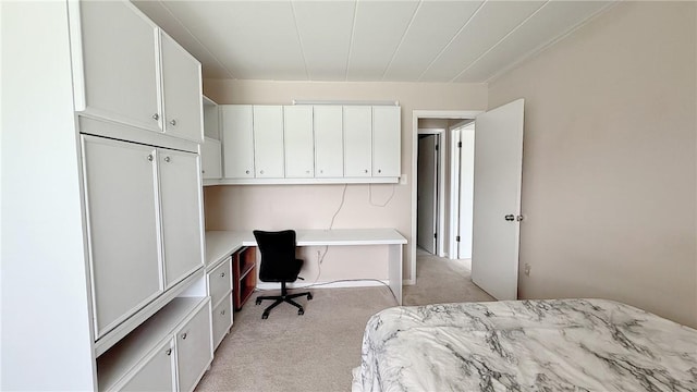 bedroom with built in desk and light carpet