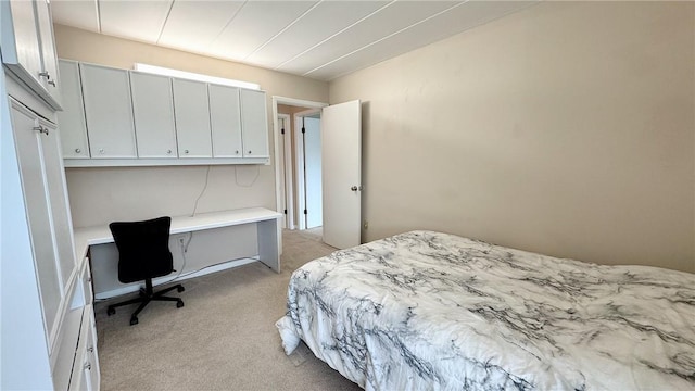 bedroom with built in desk and light carpet