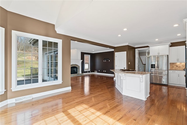 kitchen with white cabinets, visible vents, stainless steel appliances, and a glass covered fireplace