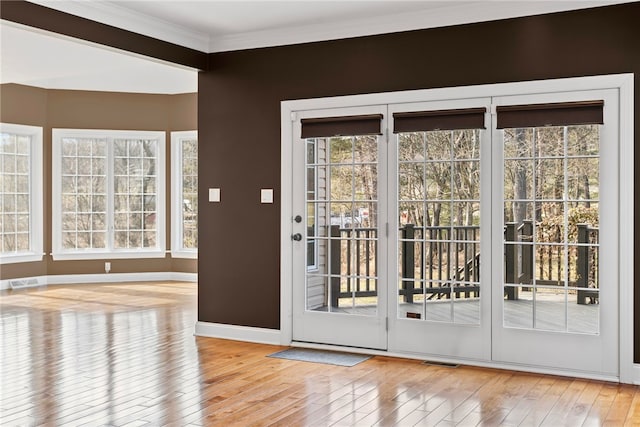 doorway with plenty of natural light, visible vents, ornamental molding, and wood-type flooring