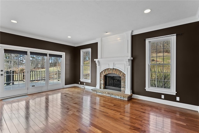 unfurnished living room with crown molding, a fireplace, baseboards, and hardwood / wood-style floors