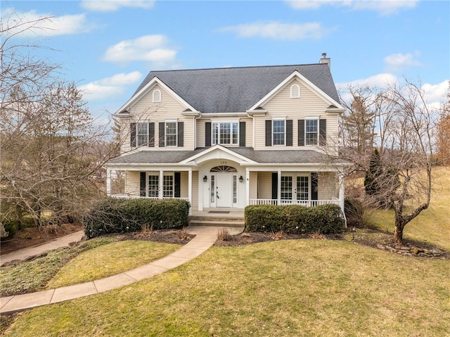 traditional-style home featuring a shingled roof, covered porch, a chimney, and a front lawn