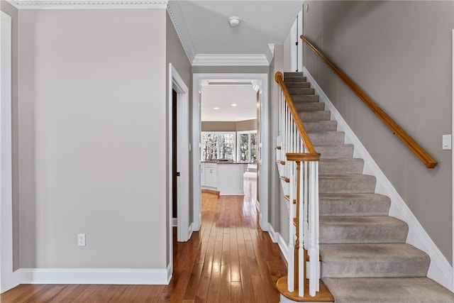 stairs featuring baseboards, hardwood / wood-style flooring, and crown molding