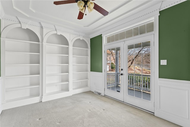 interior space featuring a tray ceiling, french doors, visible vents, carpet flooring, and wainscoting