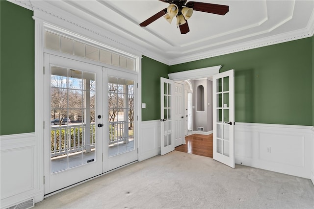 doorway to outside featuring a wainscoted wall, a tray ceiling, french doors, and visible vents