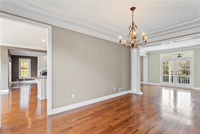 unfurnished room featuring crown molding, a fireplace, visible vents, light wood-style floors, and baseboards