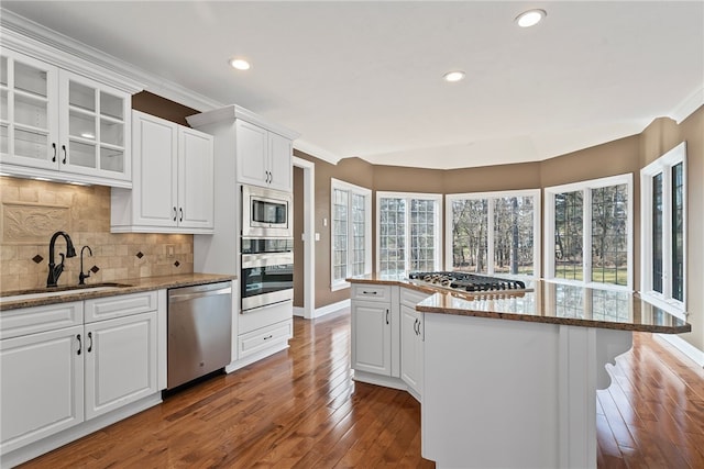 kitchen with stainless steel appliances, glass insert cabinets, white cabinets, a sink, and hardwood / wood-style floors