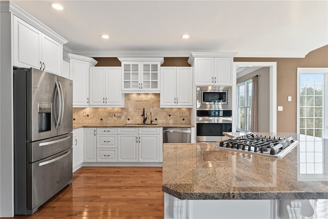 kitchen with stainless steel appliances, tasteful backsplash, a sink, and white cabinetry