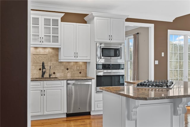 kitchen featuring stainless steel appliances, a sink, white cabinets, and crown molding