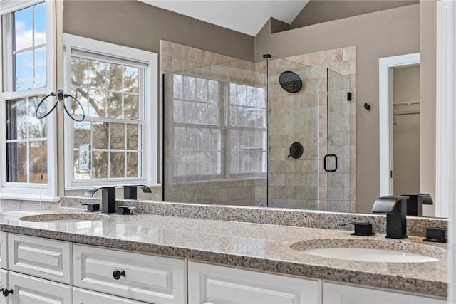 full bathroom with lofted ceiling, a stall shower, double vanity, and a sink