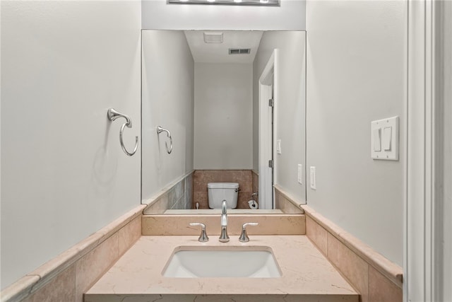 bathroom with toilet, vanity, and visible vents