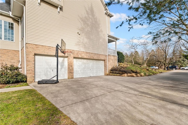 view of side of property with a garage, concrete driveway, and brick siding