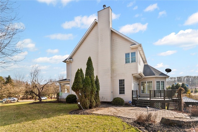 view of side of property featuring a yard, a chimney, and a wooden deck