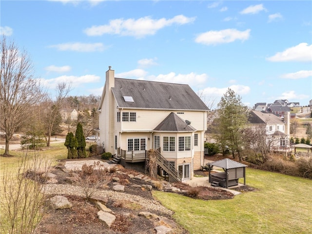 rear view of house with a lawn, a chimney, a wooden deck, and stairs