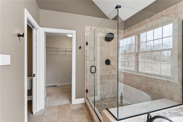 bathroom featuring plenty of natural light, a shower stall, visible vents, and a walk in closet