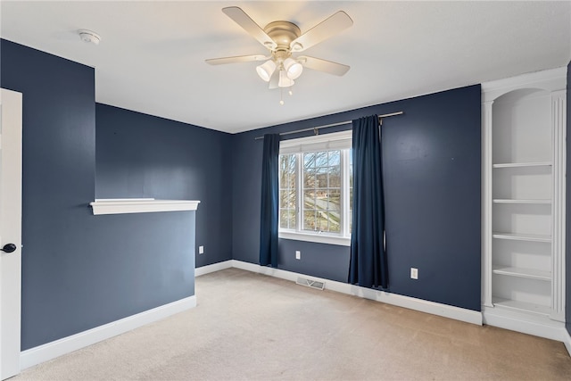 carpeted empty room featuring a ceiling fan, visible vents, and baseboards