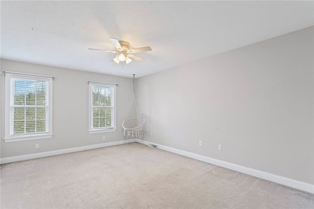 empty room with baseboards, visible vents, and light colored carpet