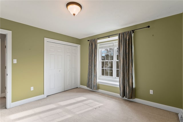 unfurnished bedroom with baseboards, a closet, and light colored carpet