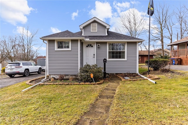 bungalow-style house with driveway, a shingled roof, and a front yard