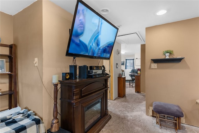 living area with attic access and a glass covered fireplace