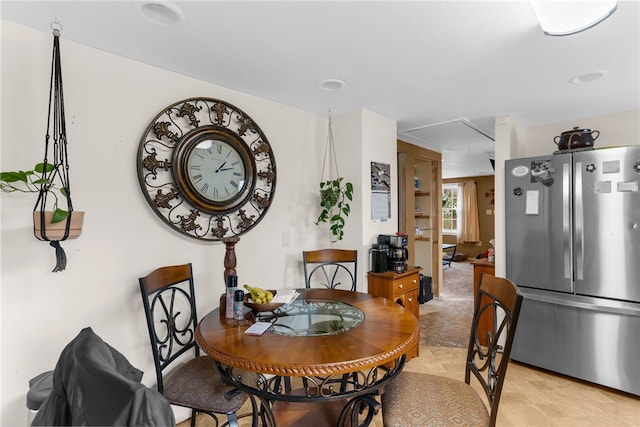 dining area featuring attic access and light colored carpet