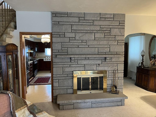 interior details featuring carpet, arched walkways, a fireplace, and range with gas cooktop