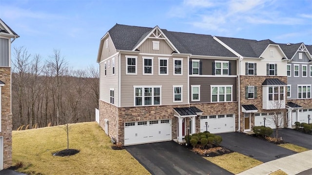 multi unit property featuring stone siding, aphalt driveway, a front lawn, and an attached garage