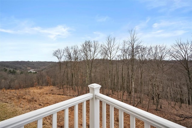 view of yard with a balcony and a wooded view