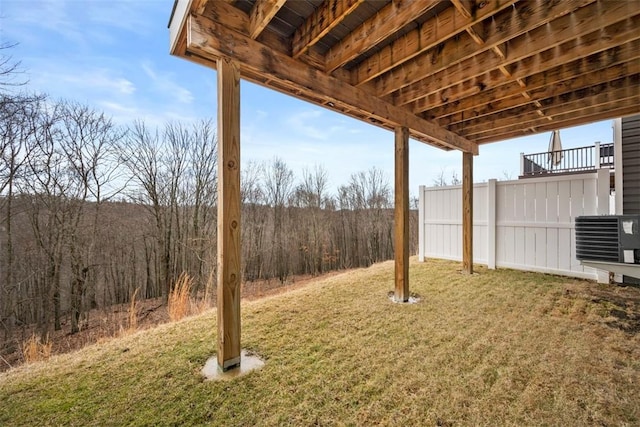 view of yard with a wooded view and central air condition unit