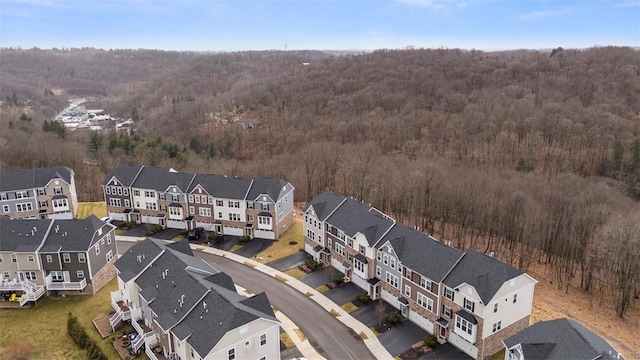 drone / aerial view featuring a wooded view and a residential view