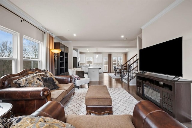 living room with stairs, ornamental molding, wood finished floors, and a wealth of natural light