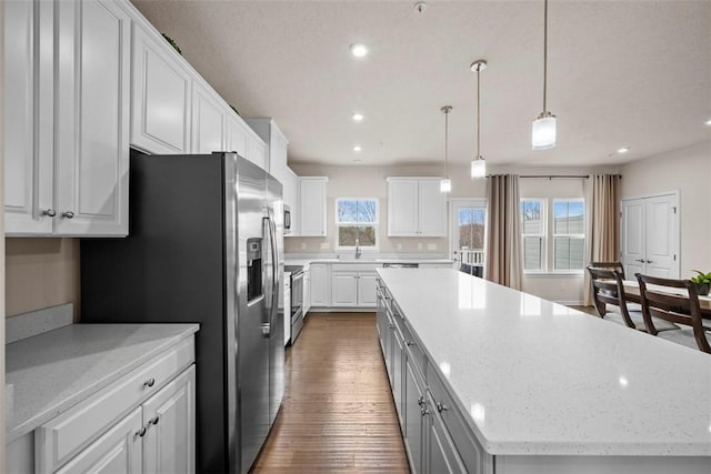 kitchen featuring white cabinets, dark wood-type flooring, a center island, stainless steel appliances, and recessed lighting