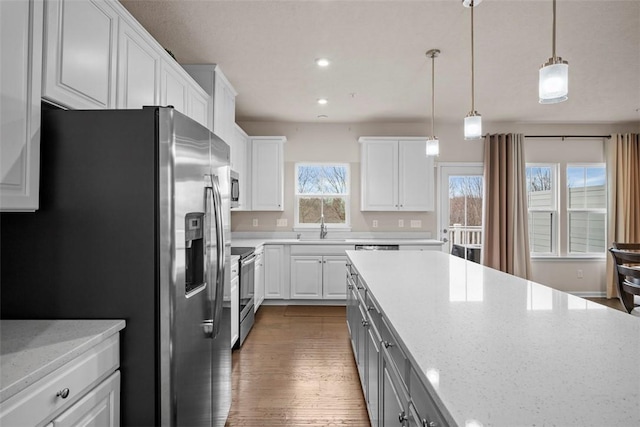 kitchen with hanging light fixtures, light stone countertops, white cabinetry, and stainless steel appliances