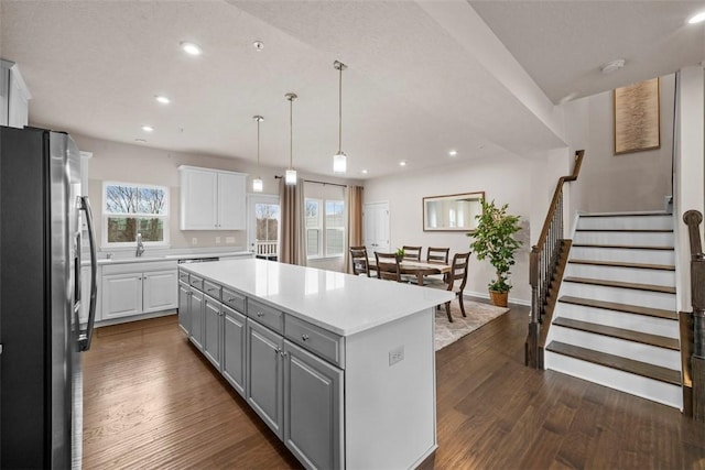 kitchen featuring dark wood-style floors, a kitchen island, freestanding refrigerator, gray cabinets, and white cabinetry