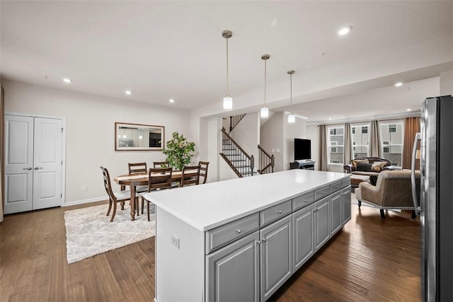 kitchen with open floor plan, gray cabinets, freestanding refrigerator, a center island, and dark wood-style floors