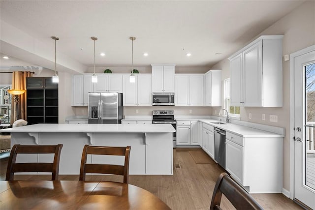 kitchen featuring appliances with stainless steel finishes, a center island, white cabinetry, and a sink