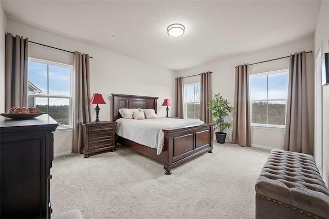 bedroom with multiple windows, visible vents, and light colored carpet