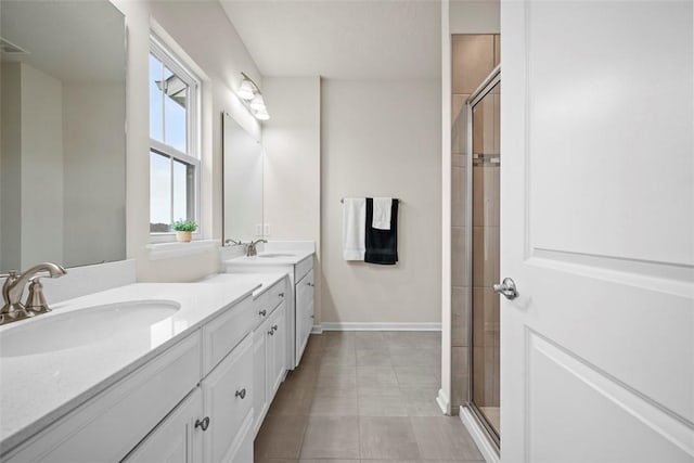 bathroom with double vanity, a shower stall, baseboards, and a sink