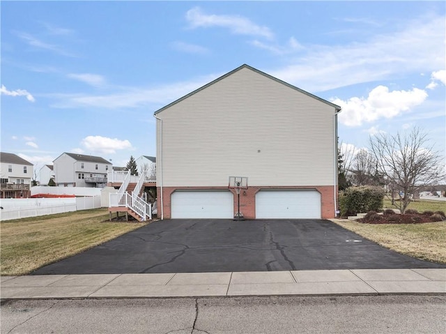 view of property exterior featuring aphalt driveway, brick siding, a lawn, stairway, and a garage