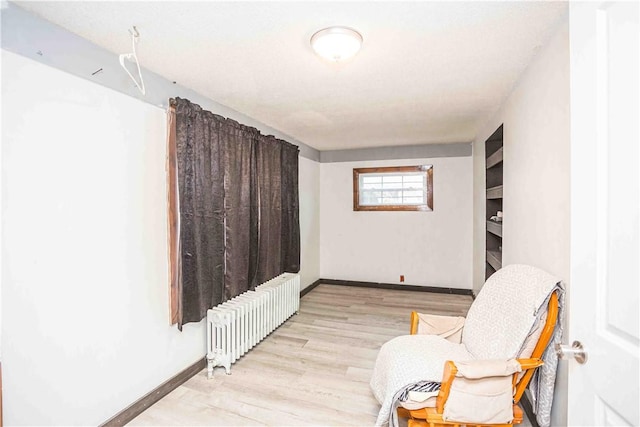 sitting room featuring light wood finished floors, radiator heating unit, and baseboards