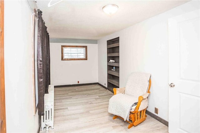 sitting room featuring light wood-type flooring, radiator heating unit, and baseboards