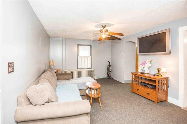 carpeted living room featuring radiator heating unit, baseboards, and a ceiling fan