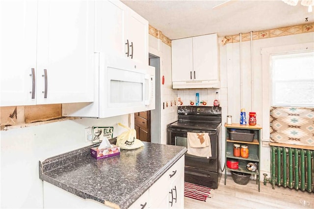 kitchen featuring white microwave, under cabinet range hood, white cabinets, black electric range, and light wood-type flooring