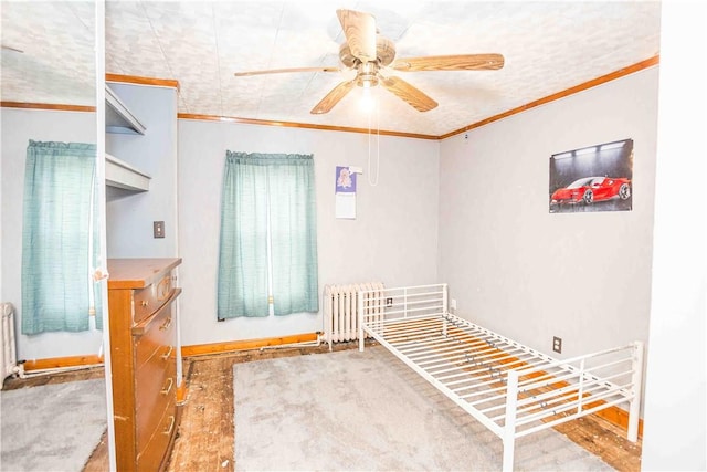 bedroom featuring a ceiling fan, radiator, crown molding, and wood finished floors