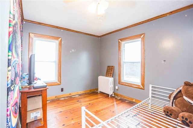 interior space featuring a wealth of natural light, radiator, crown molding, and hardwood / wood-style flooring