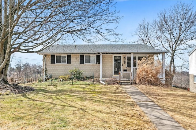 view of front of property featuring covered porch, a front lawn, and brick siding